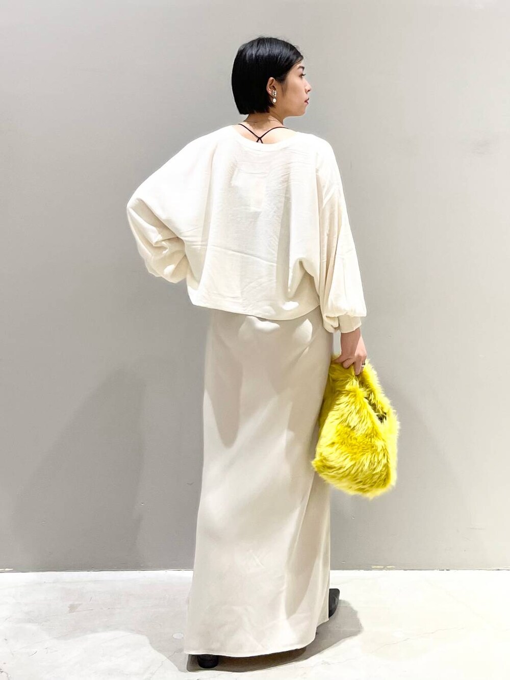 ブラック系のキャミソール、ホワイト系のニット/セーター、イエロー系のハンドバッグを着用したレディースの秋コーディネートの6枚目の写真