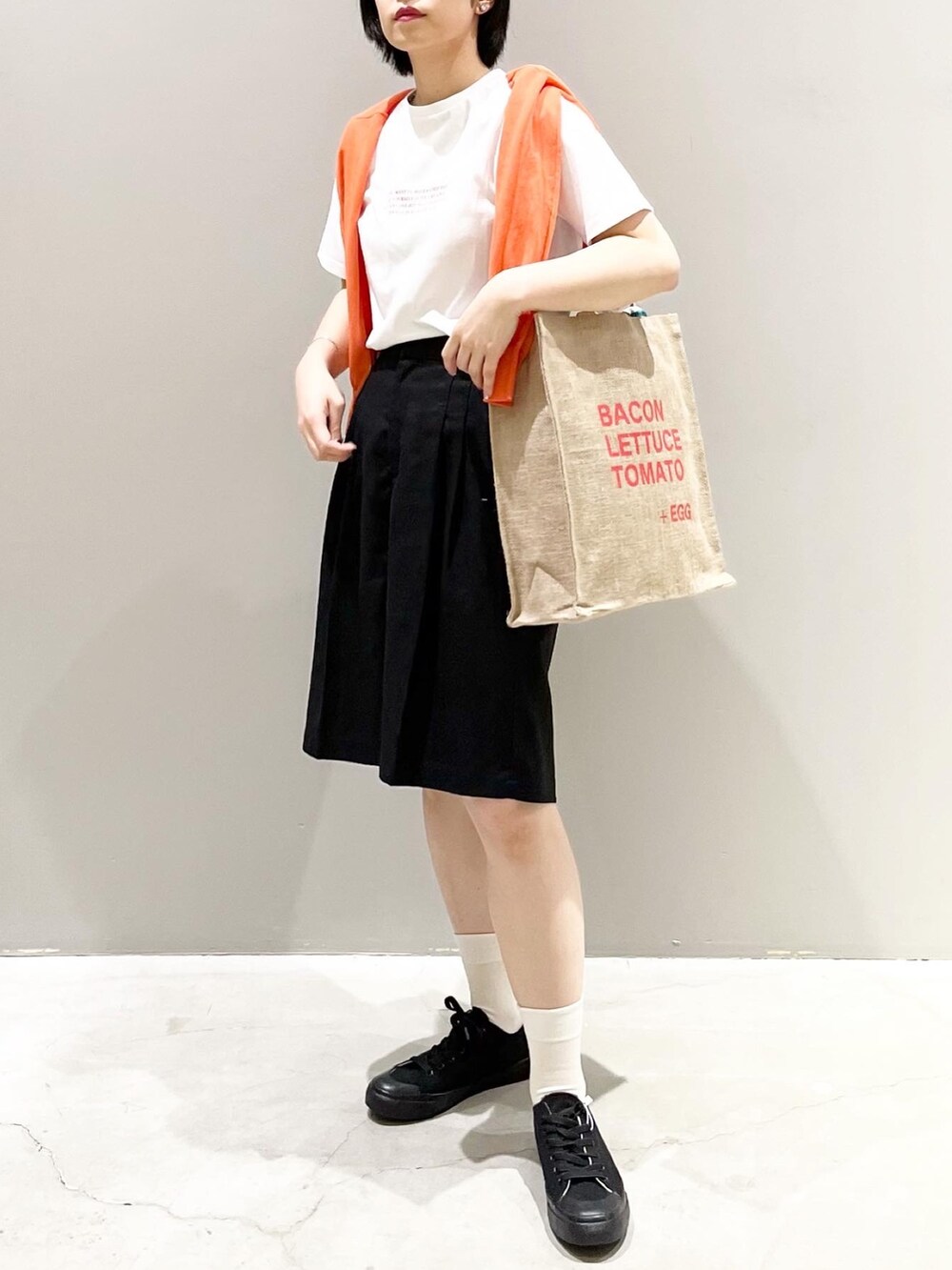 ブラック系のその他パンツ、ブラック系のスニーカー、オレンジ系のトートバッグを着用したレディースの夏コーディネートの2枚目の写真