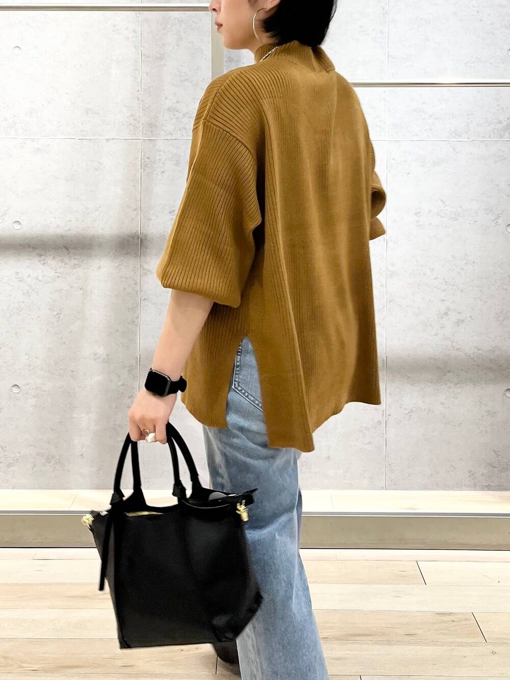 ブラウン系のニット/セーター、ブルー系のデニムパンツ、ベージュ系のショルダーバッグを着用したレディースの秋コーディネートの4枚目の写真