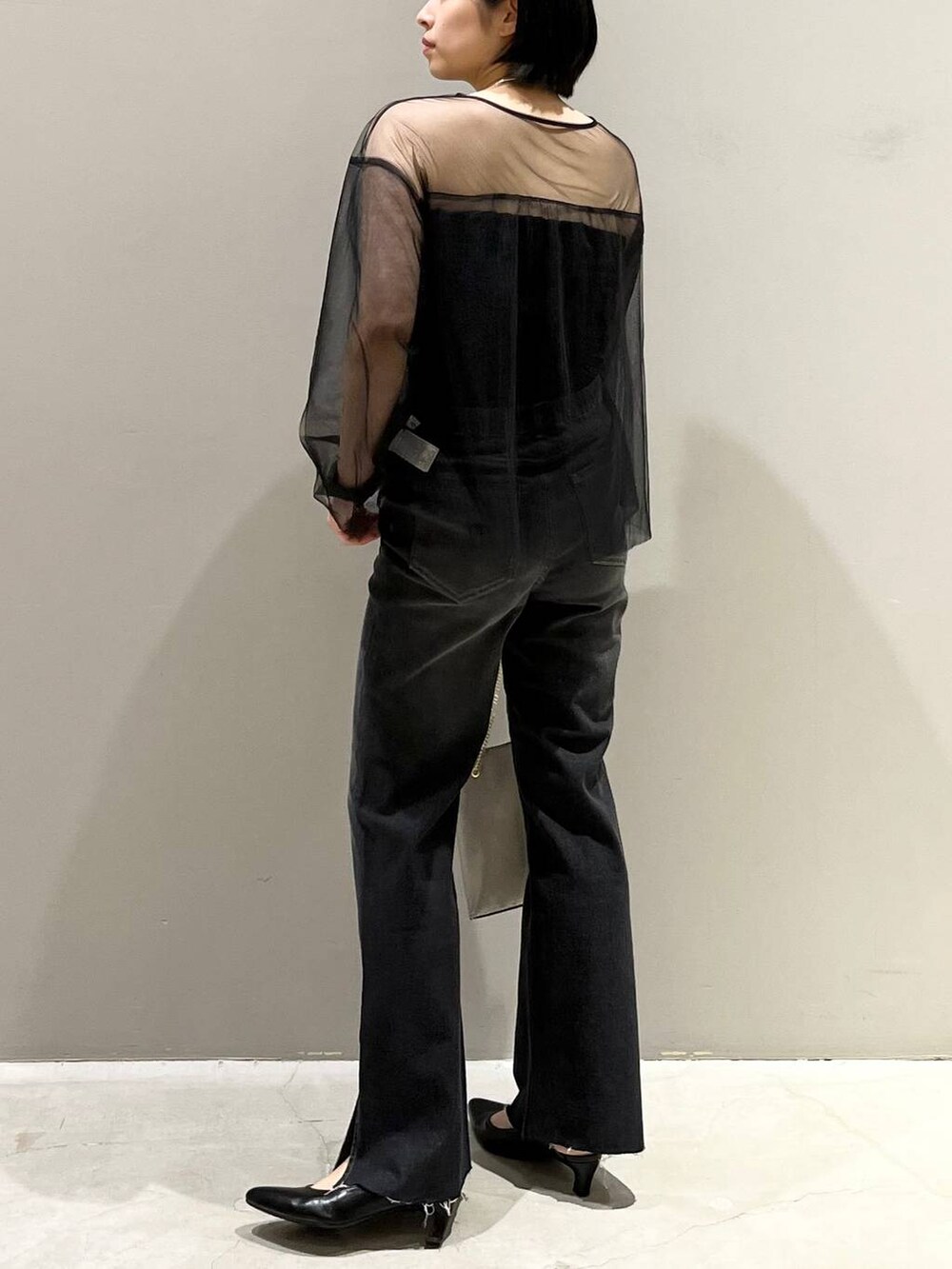 ブラック系のチューブトップ、ブラック系のTシャツ/カットソー、ブラック系のデニムパンツを着用したレディースの秋コーディネートの5枚目の写真