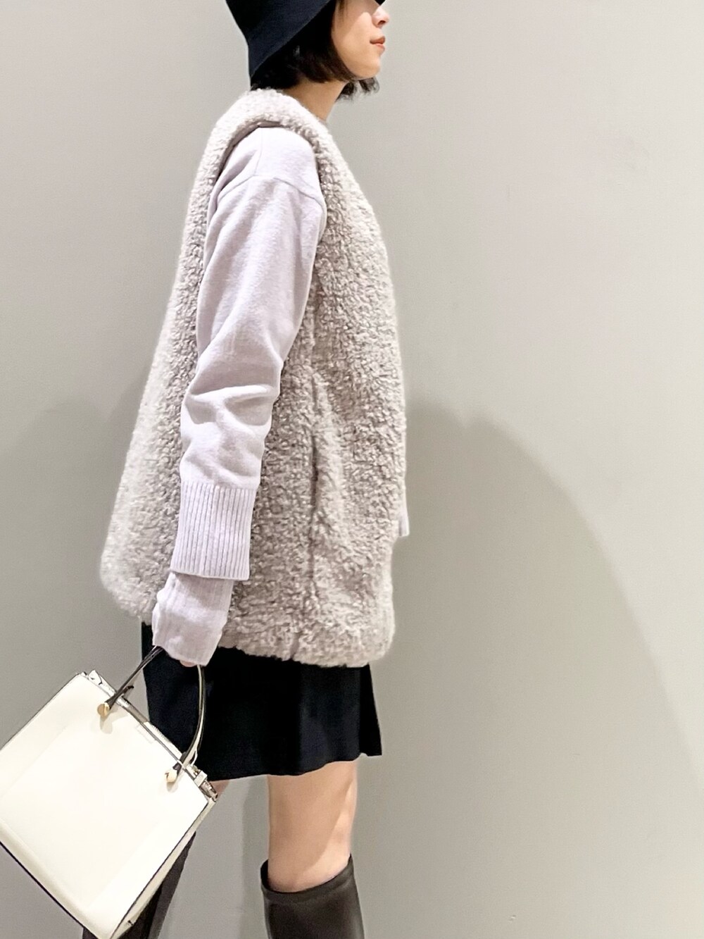 ブラウン系のブーツ、ホワイト系のショルダーバッグ、ブラック系のパンツを着用したレディースの冬コーディネートの5枚目の写真