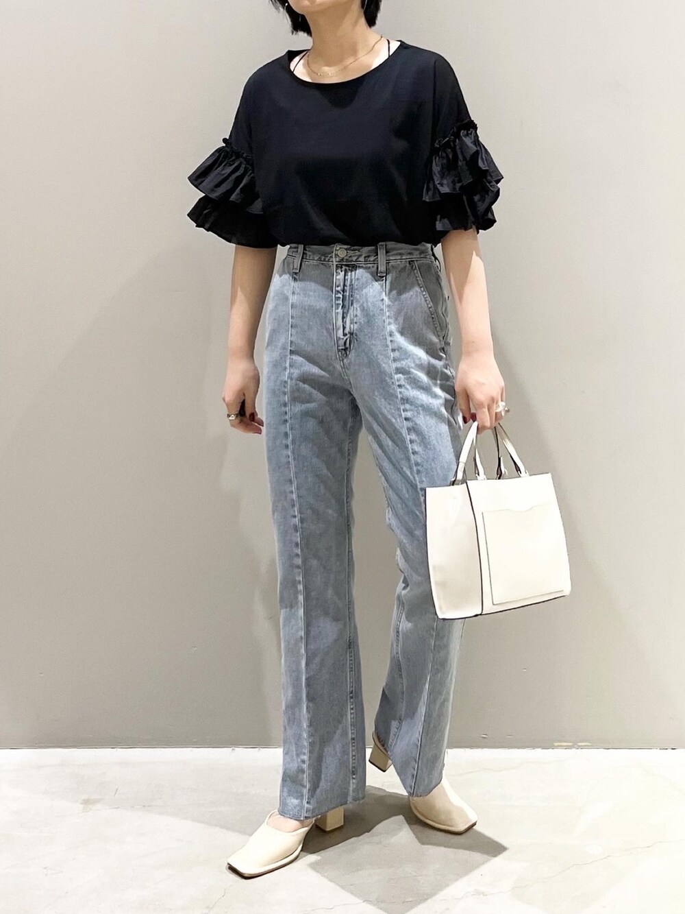 ブルー系のデニムパンツ、ホワイト系のショルダーバッグ、ホワイト系のパンプスを着用したレディースの夏コーディネートの5枚目の写真