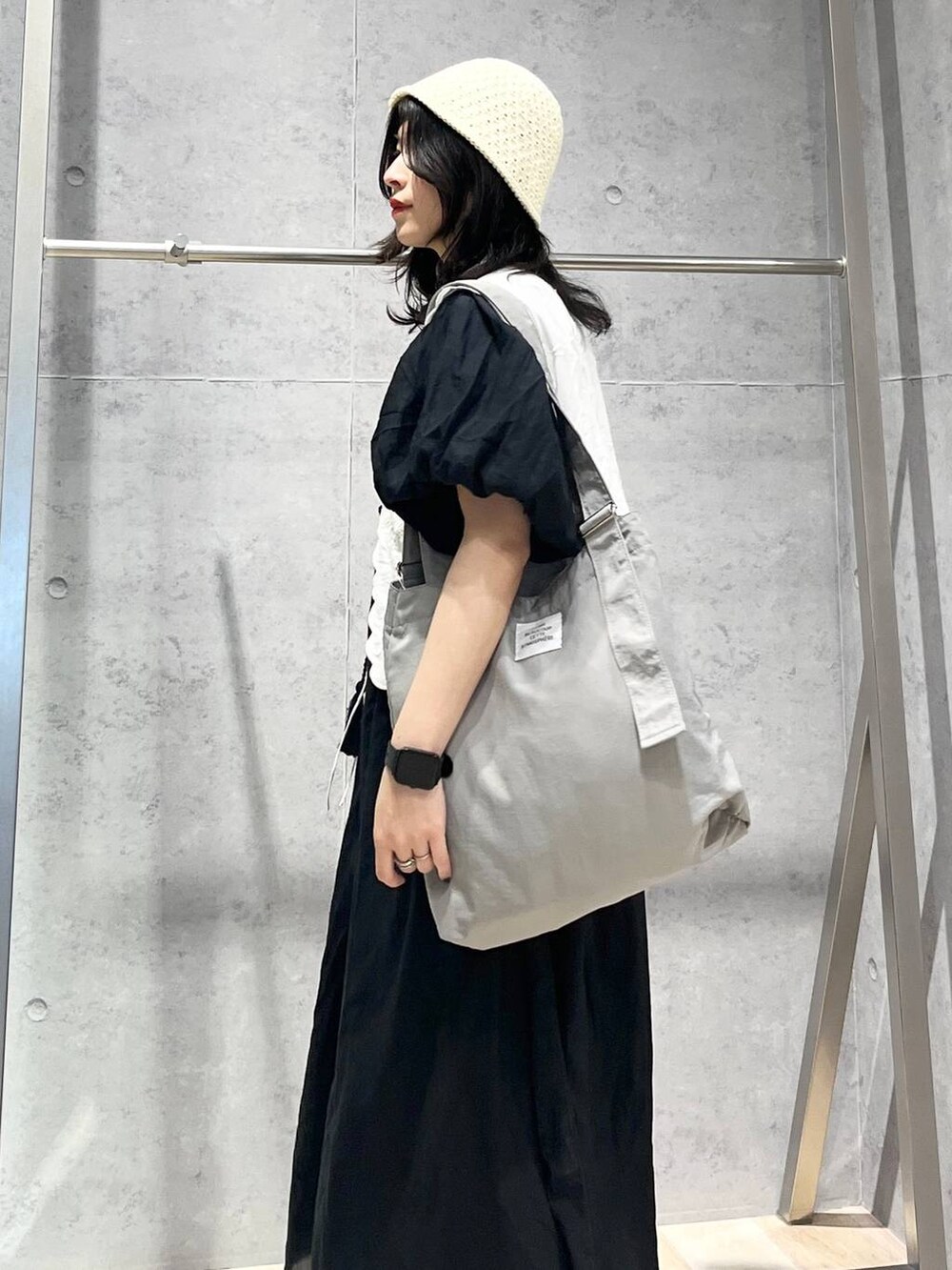 ブラック系のワンピース、ホワイト系のサンダル、ホワイト系のベストを着用したレディースの春コーディネートの6枚目の写真