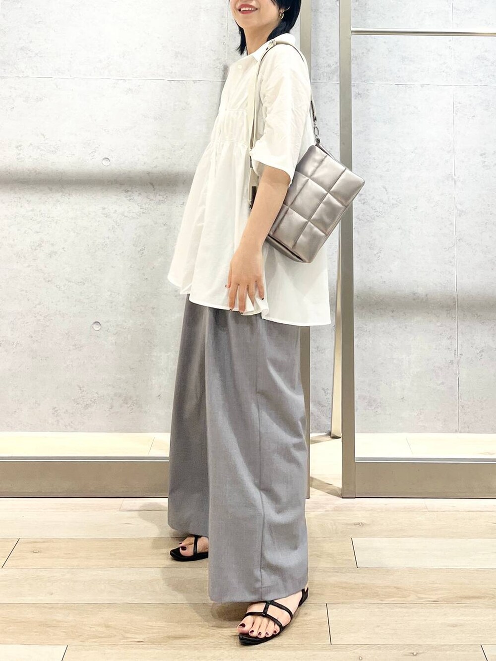 ブラック系のサンダル、ブラック系のハンドバッグ、グレー系のスラックスを着用したレディースの夏コーディネートの6枚目の写真