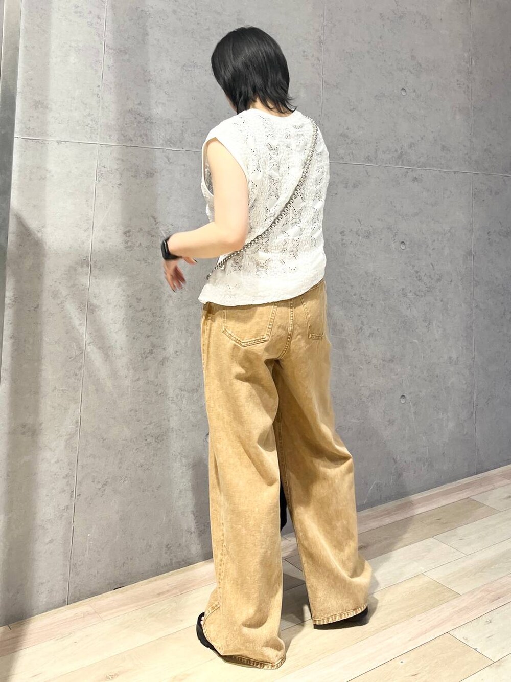 ブラック系のショルダーバッグ、ブラウン系のデニムパンツ、ブラック系のサンダルを着用したレディースの夏コーディネートの4枚目の写真