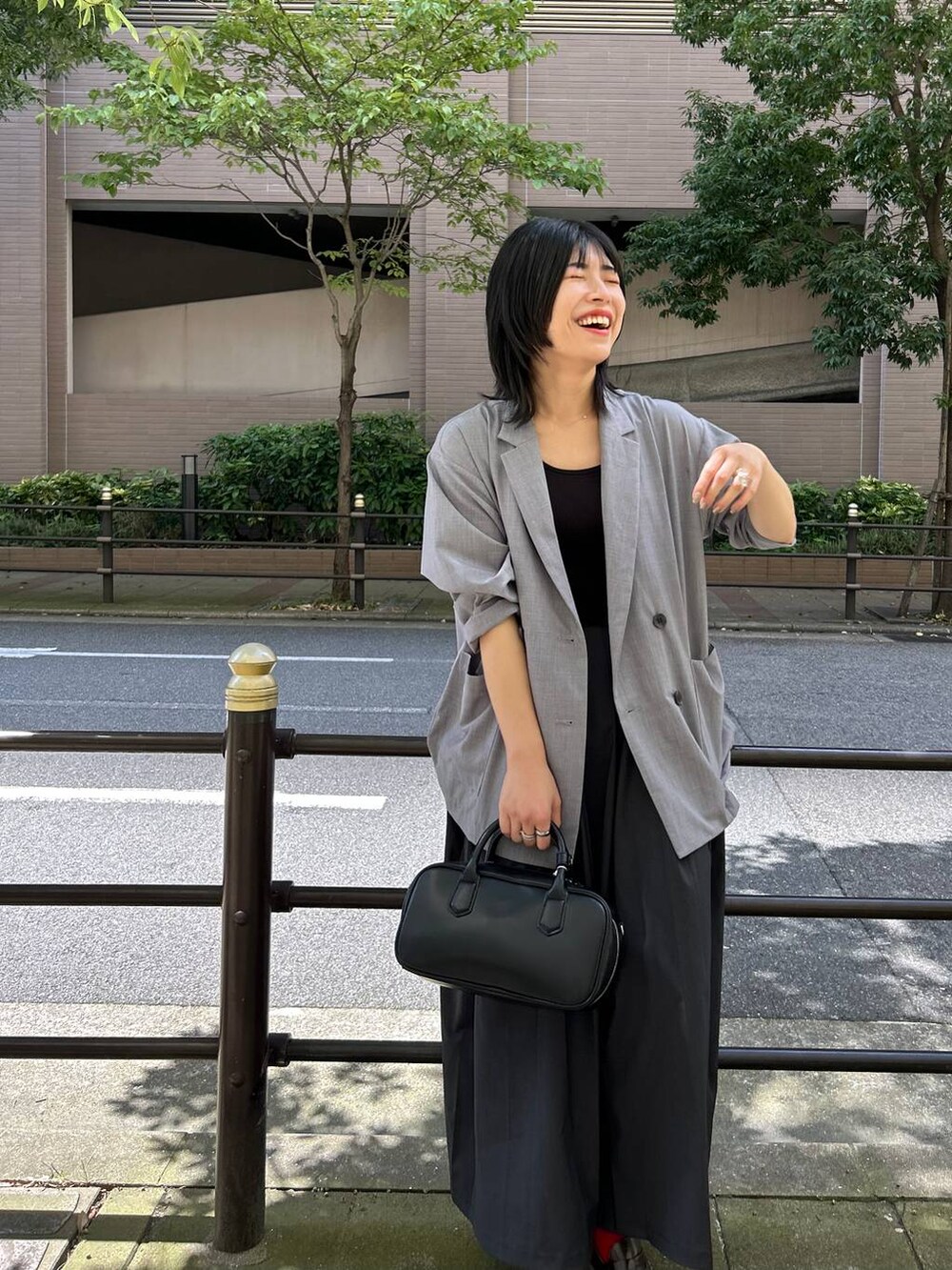 ブラック系のボストンバッグ、グレー系のテーラードジャケット、グレー系のスカートを着用したレディースの夏コーディネートの6枚目の写真