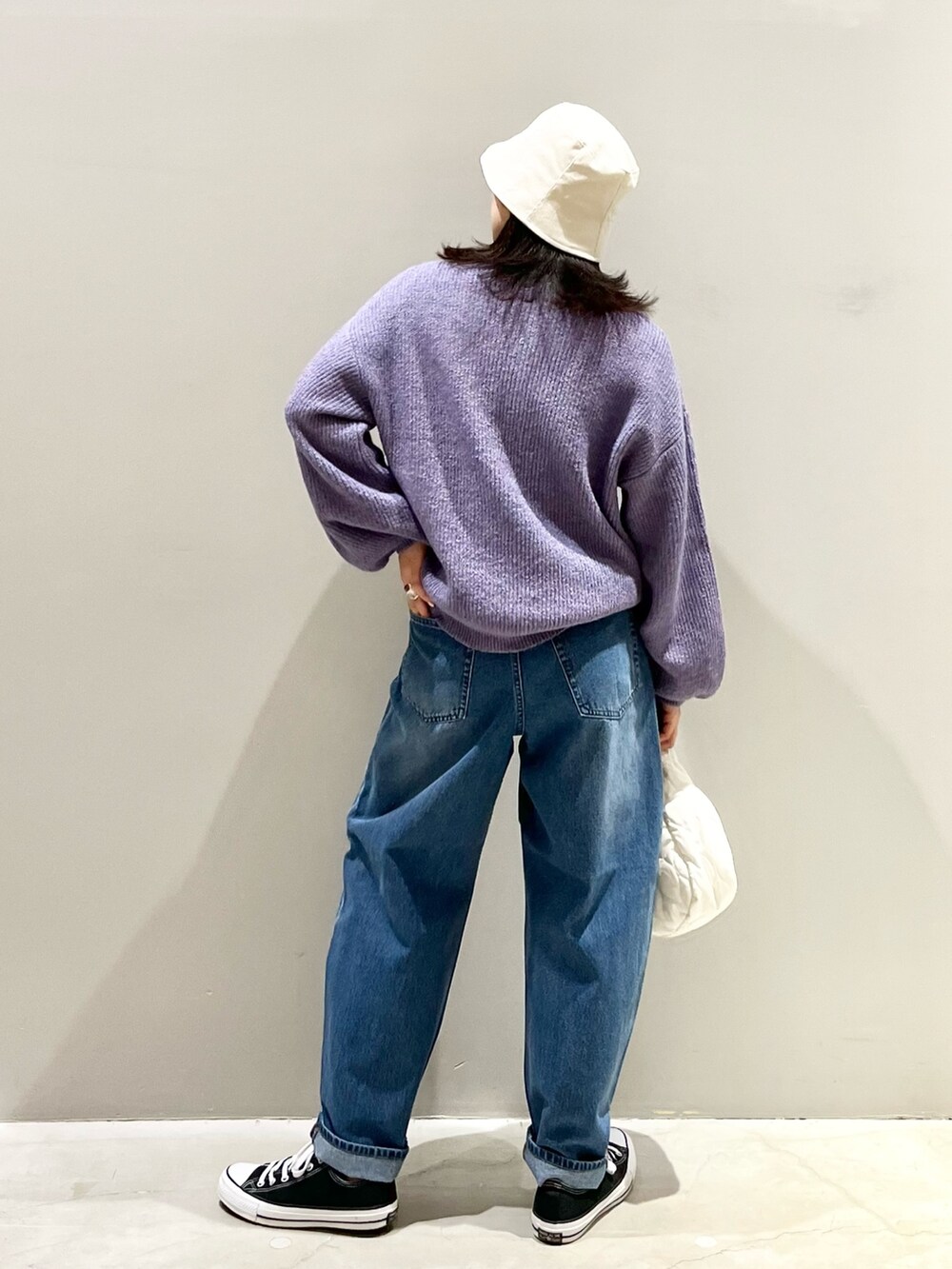 ホワイト系のバッグ、ブルー系のデニムパンツ、パープル系のニット/セーターを着用したレディースの冬コーディネートの4枚目の写真