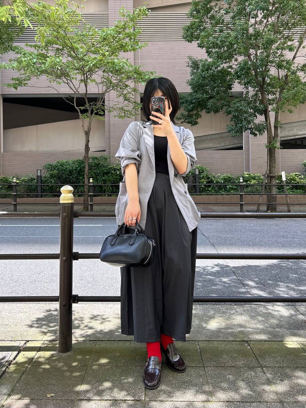 ブラック系のボストンバッグ、グレー系のテーラードジャケット、グレー系のスカートを着用したレディースの夏コーディネートの4枚目の写真