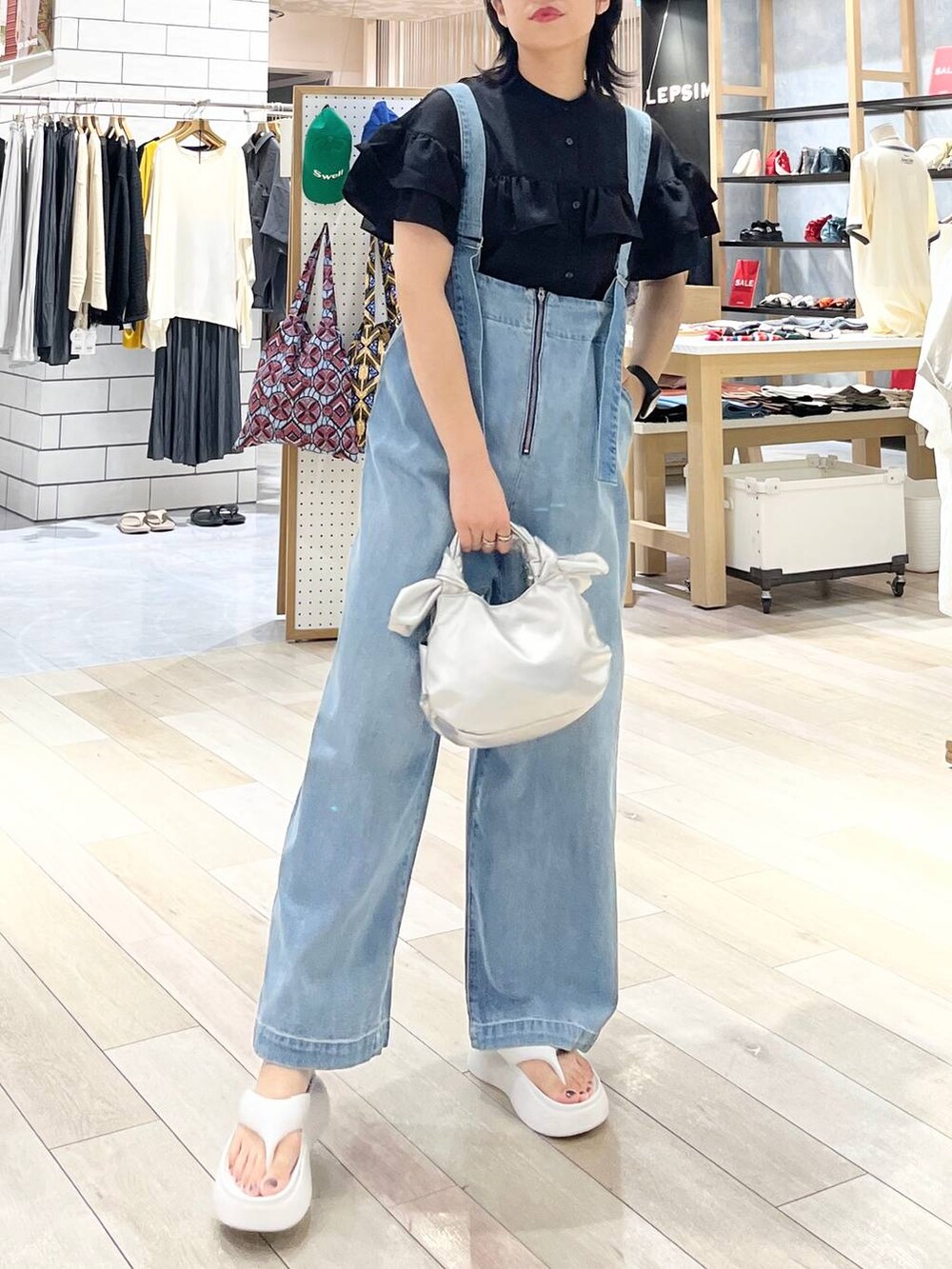 ホワイト系のサンダル、ブルー系のデニムパンツ、シルバー系のショルダーバッグを着用したレディースの夏コーディネートの9枚目の写真