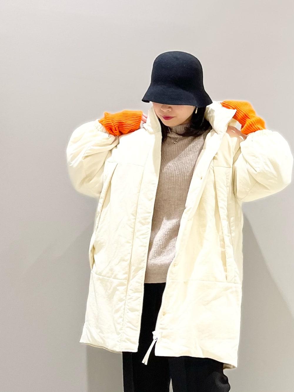 ブラウン系のニット/セーター、ホワイト系のジャケット/アウター、ブラック系のパンツを着用したレディースの冬コーディネートの2枚目の写真