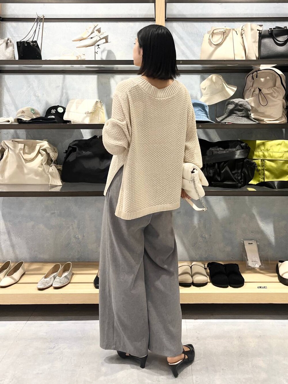 ホワイト系のショルダーバッグ、ホワイト系のニット/セーター、グレー系のスラックスを着用したレディースの春コーディネートの7枚目の写真