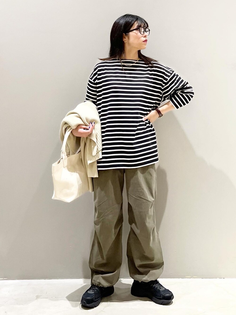グリーン系のカーゴパンツ、ホワイト系のトートバッグ、ブラック系のスニーカーを着用したレディースの秋コーディネートの2枚目の写真