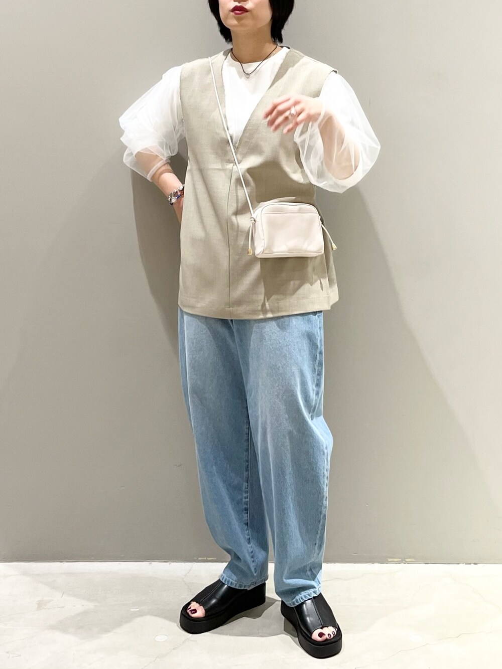 ブルー系のデニムパンツ、ホワイト系のサンダル、ブラック系のバッグを着用したレディースの春コーディネートの4枚目の写真