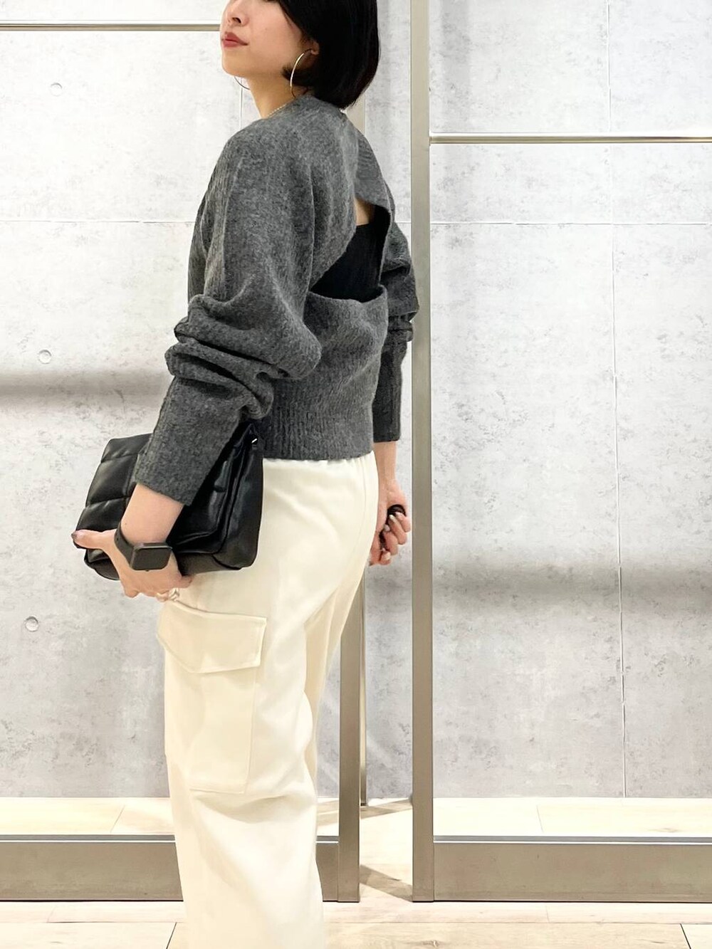 ブラック系のショルダーバッグ、ブラック系のパンプス、グレー系のニット/セーターを着用したレディースの秋コーディネートの3枚目の写真