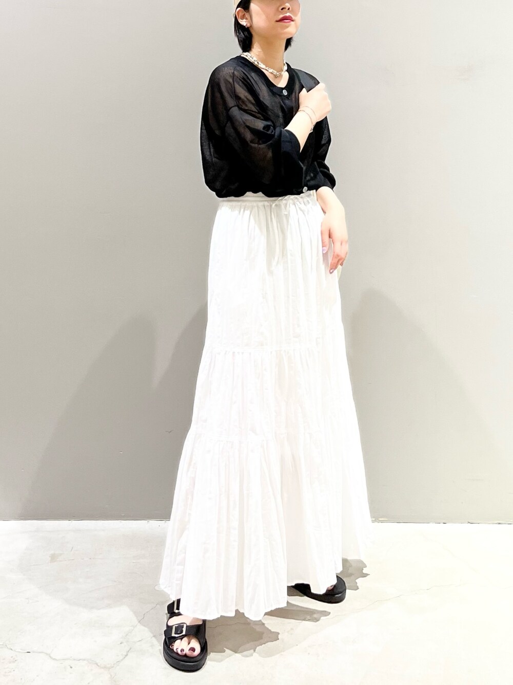 ブラック系のサンダル、ホワイト系のスカート、ホワイト系のショルダーバッグを着用したレディースの夏コーディネートの2枚目の写真