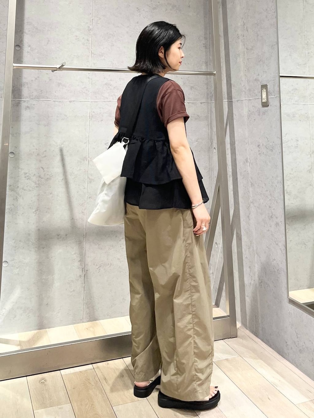 ホワイト系のサンダル、ブラック系のベスト、ブラウン系のTシャツ/カットソーを着用したレディースの夏コーディネートの3枚目の写真