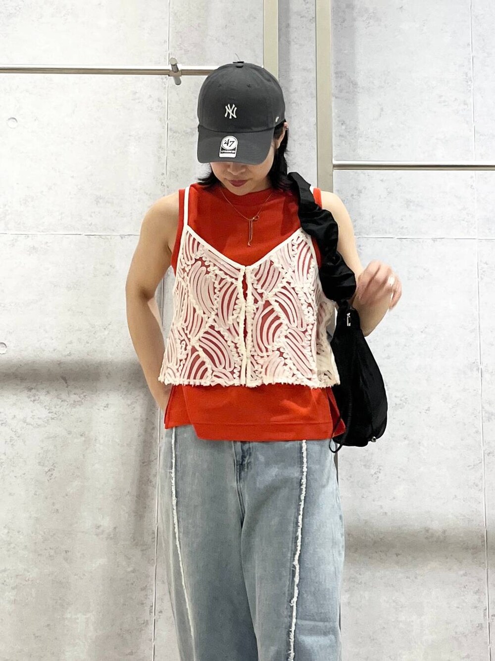 オレンジ系のタンクトップ、ブラック系のショルダーバッグ、ブルー系のデニムパンツを着用したレディースの夏コーディネートの8枚目の写真