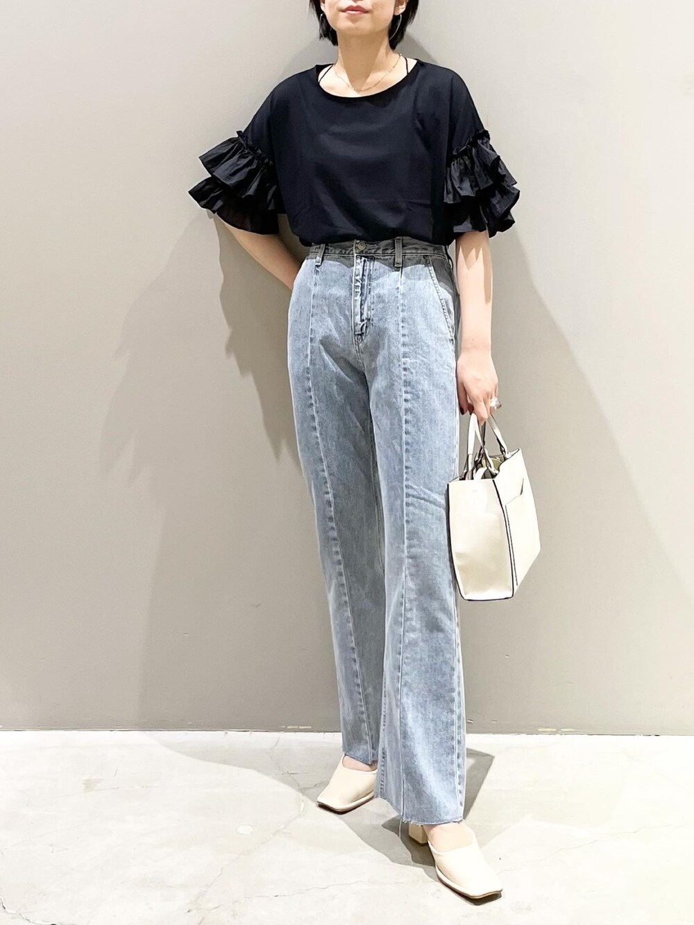 ブルー系のデニムパンツ、ホワイト系のショルダーバッグ、ホワイト系のパンプスを着用したレディースの夏コーディネートの3枚目の写真