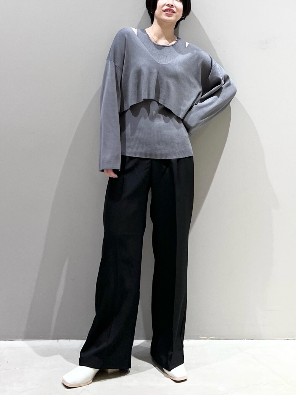 グレー系のニット/セーター、ブラック系のパンツ、ホワイト系のシューズを着用したレディースの春コーディネートの3枚目の写真