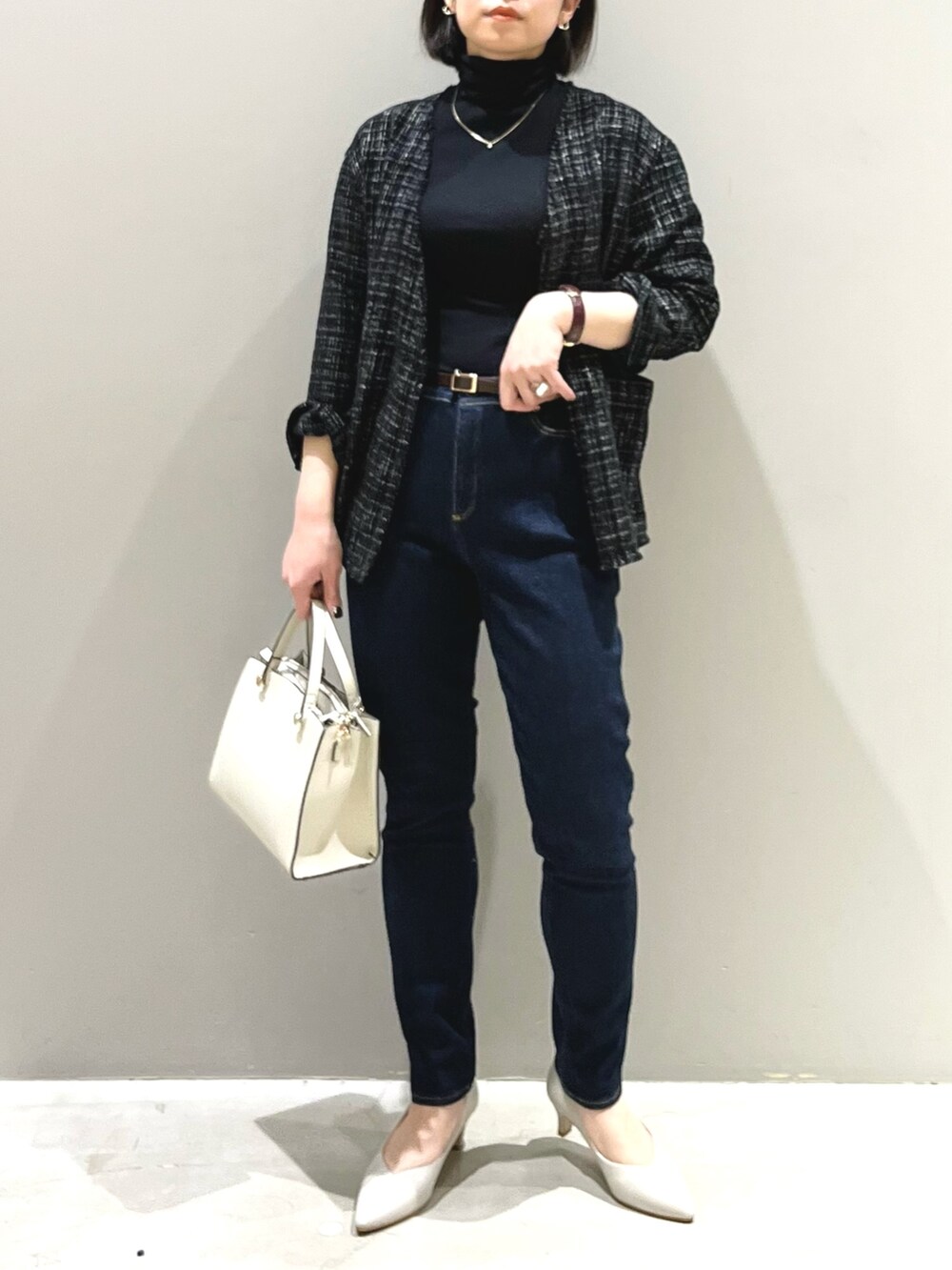ホワイト系のショルダーバッグ、ベージュ系のパンプス、ブルー系のデニムパンツを着用したレディースの春コーディネートの5枚目の写真