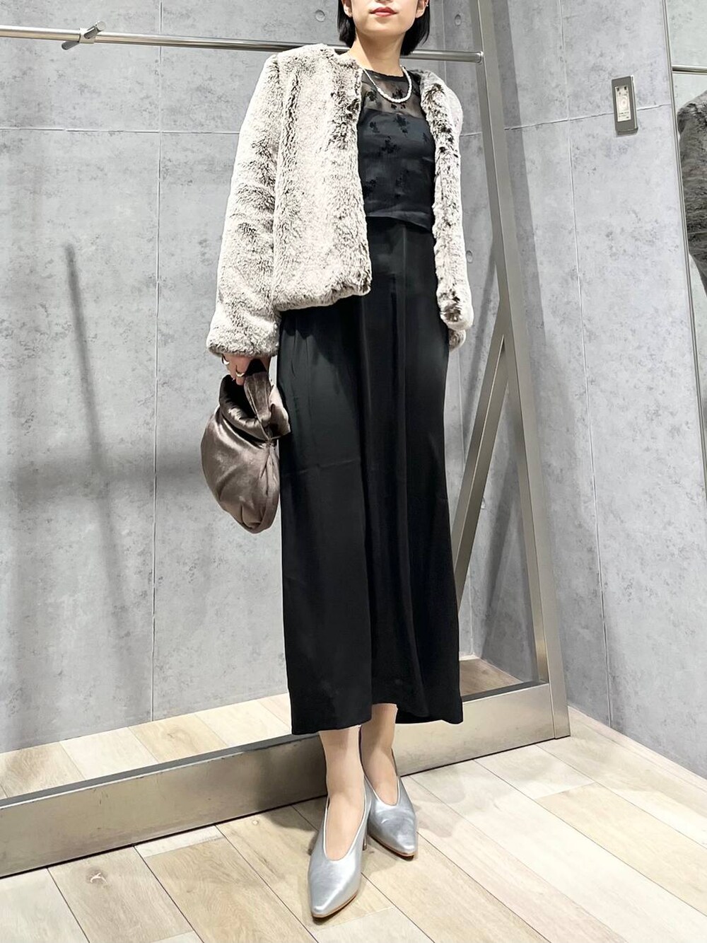 シルバー系のパンプス、ブラウン系のハンドバッグ、ベージュ系のノーカラーコートを着用したレディースの秋コーディネートの9枚目の写真