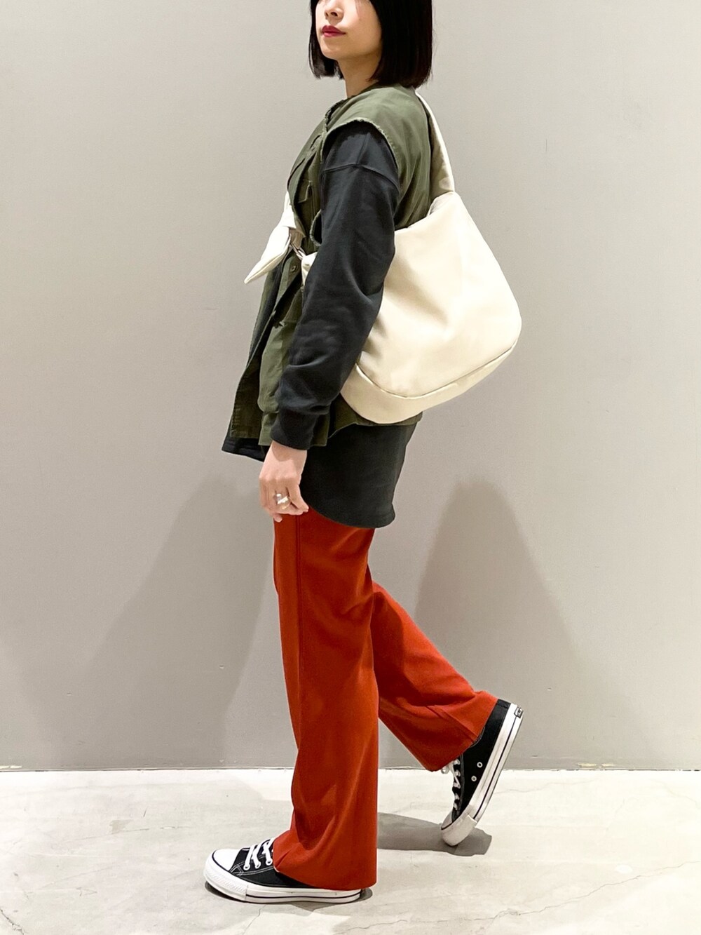 ブラック系のスニーカー、オレンジ系のその他パンツ、グリーン系のジャケット/アウターを着用したレディースの春コーディネートの2枚目の写真