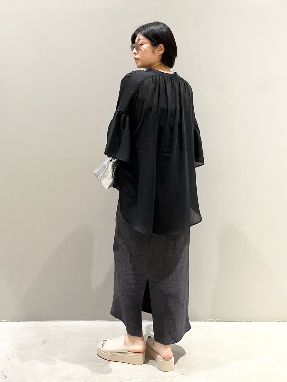 ベージュ系のサンダル、グレー系のスカート、グレー系のクラッチバッグを着用したレディースの夏コーディネートの3枚目の写真