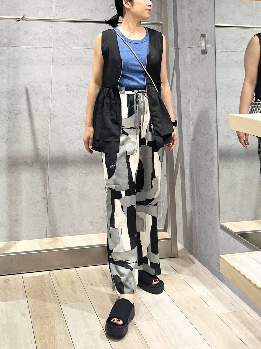 ブルー系のTシャツ/カットソー、ブラック系のサンダル、ブラック系のベストを着用したレディースの夏コーディネートの2枚目の写真