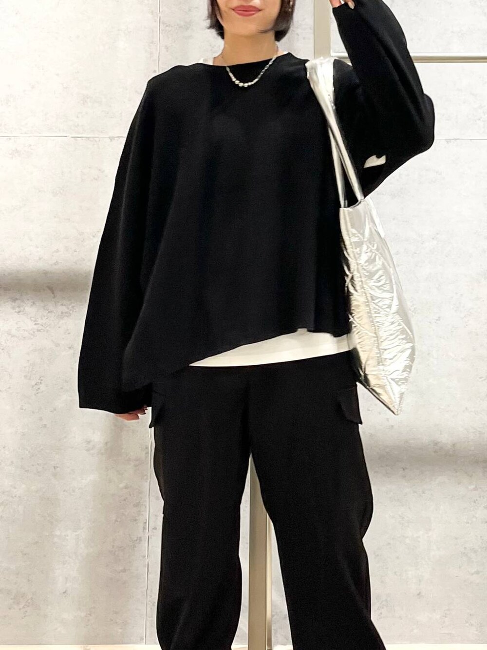 ブラック系のニット/セーター、ホワイト系のTシャツ/カットソー、ブラック系のブーツを着用したレディースの秋コーディネートの8枚目の写真