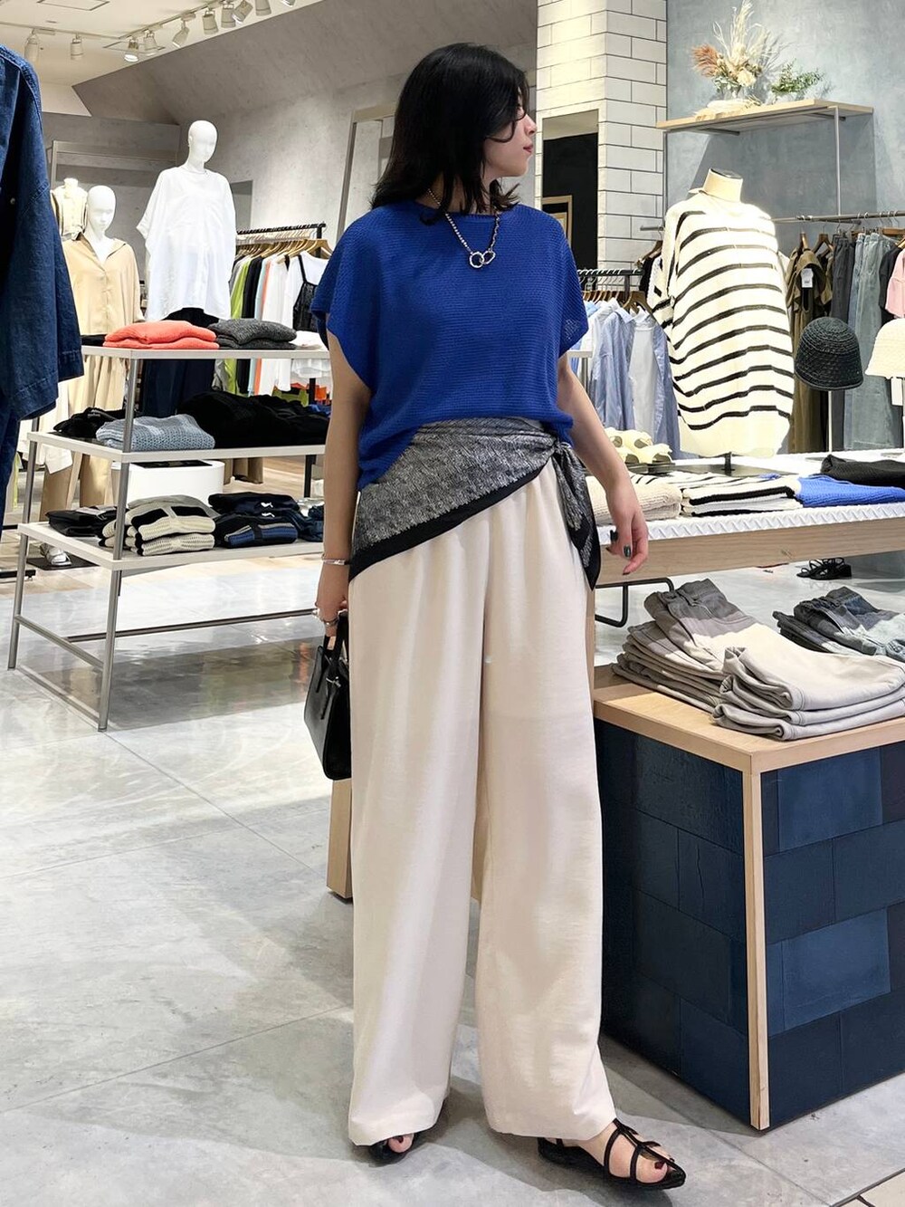 ブルー系のニット/セーター、ホワイト系のその他パンツ、ブラック系のサンダルを着用したレディースの春コーディネートの3枚目の写真