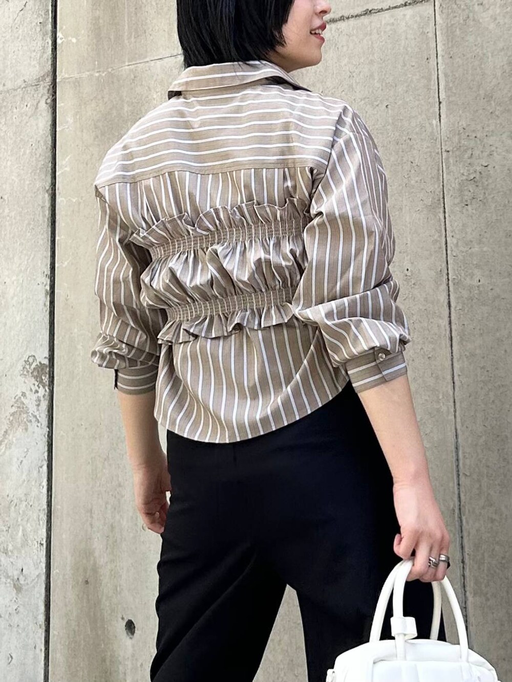 ブラック系のパンプス、ブラック系のその他パンツ、ホワイト系のボストンバッグを着用したレディースの秋コーディネートの3枚目の写真