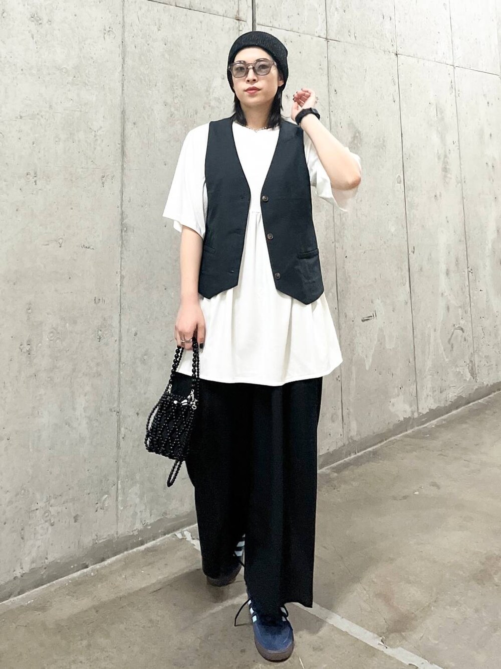 ブラック系のスラックス、ブラック系のショルダーバッグ、グレー系のベストを着用したレディースの夏コーディネートの5枚目の写真