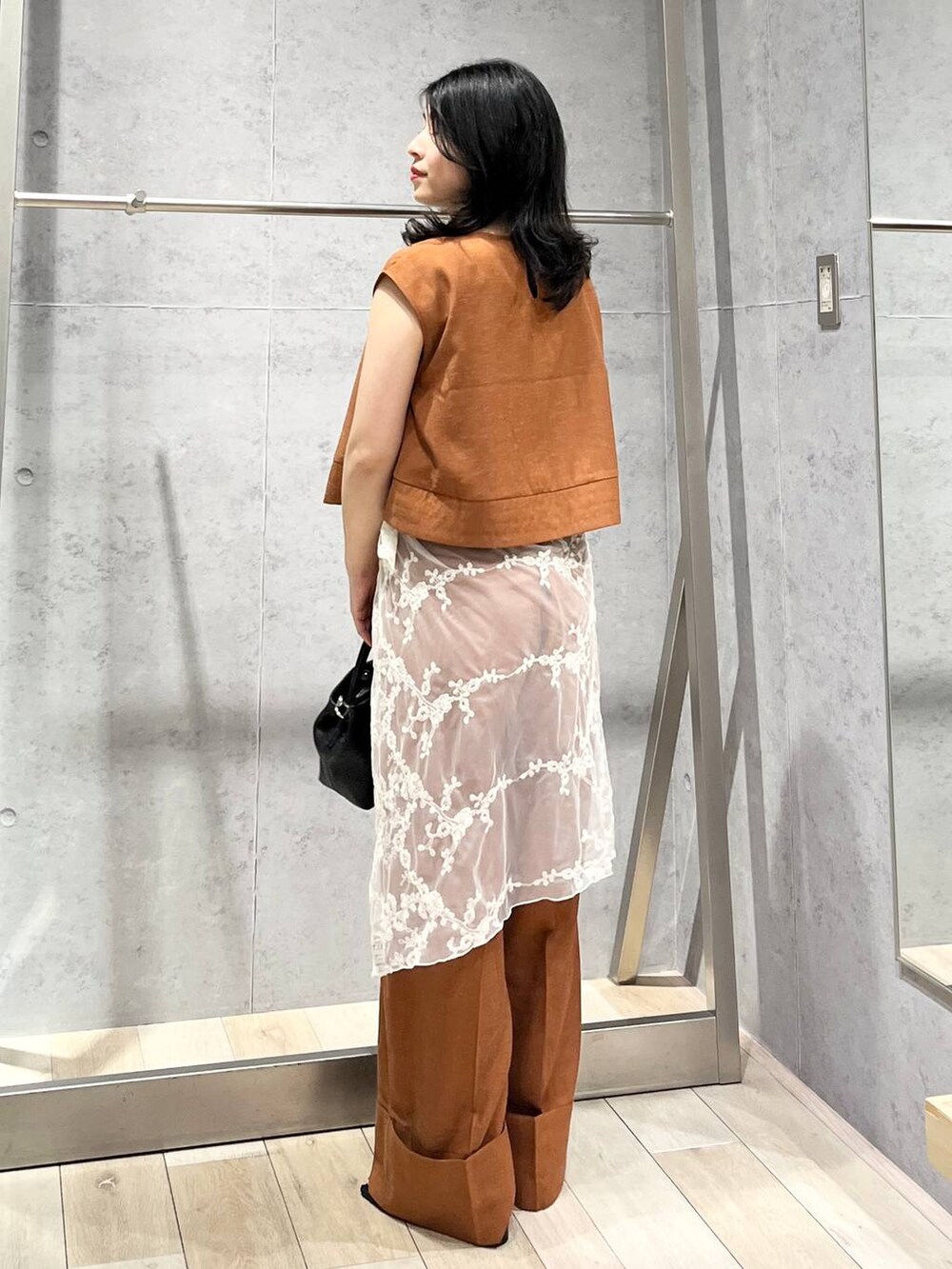 ブラック系のサンダル、オレンジ系のシャツ/ブラウス、ブラック系のショルダーバッグを着用したレディースの夏コーディネートの4枚目の写真