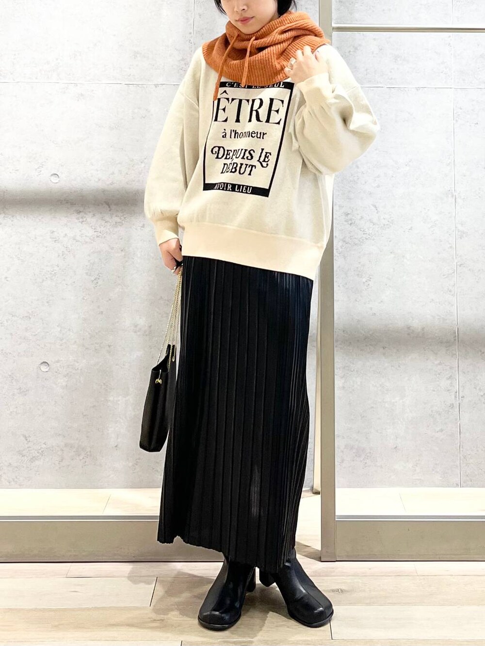 ブラック系のショルダーバッグ、ブラック系のブーツ、ホワイト系のニット/セーターを着用したレディースの秋コーディネートの3枚目の写真