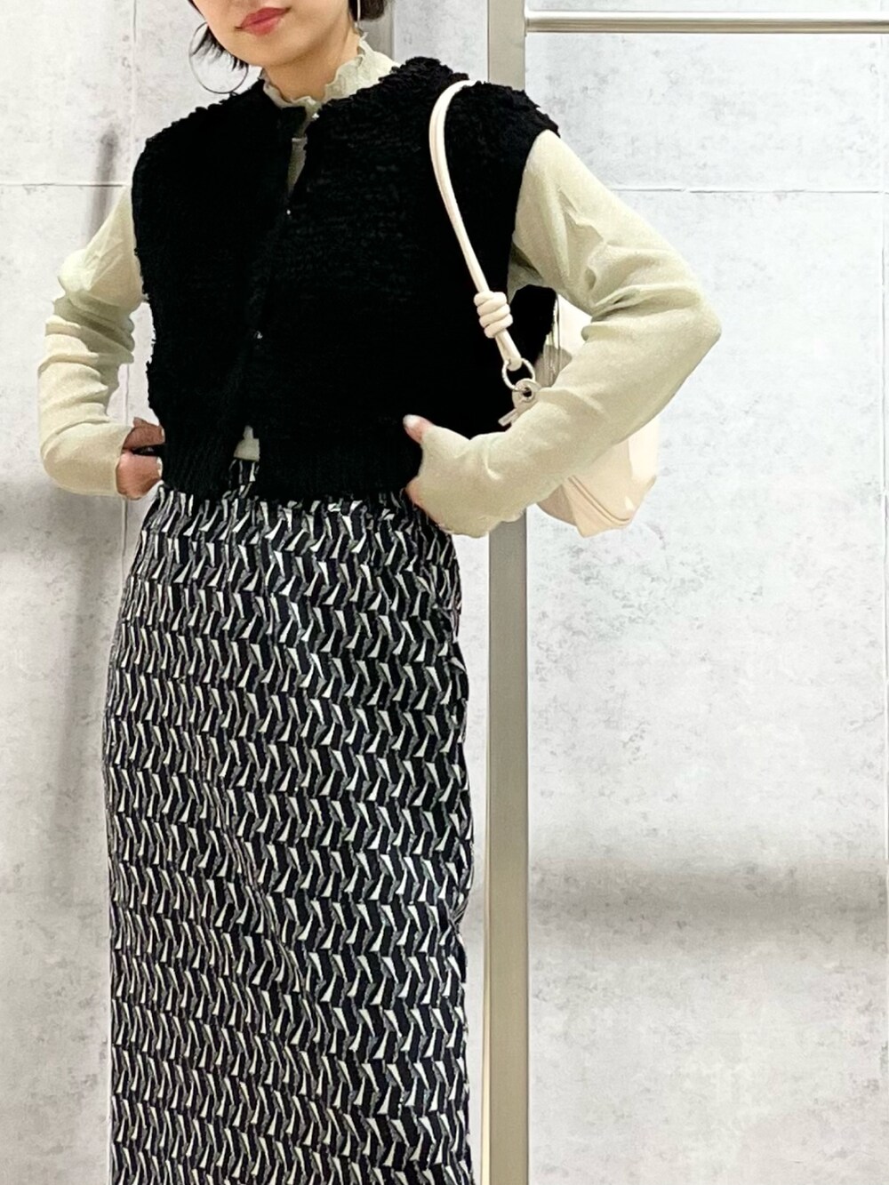 グリーン系のスカート、グリーン系のTシャツ/カットソー、ブラック系のベストを着用したレディースの秋コーディネートの5枚目の写真