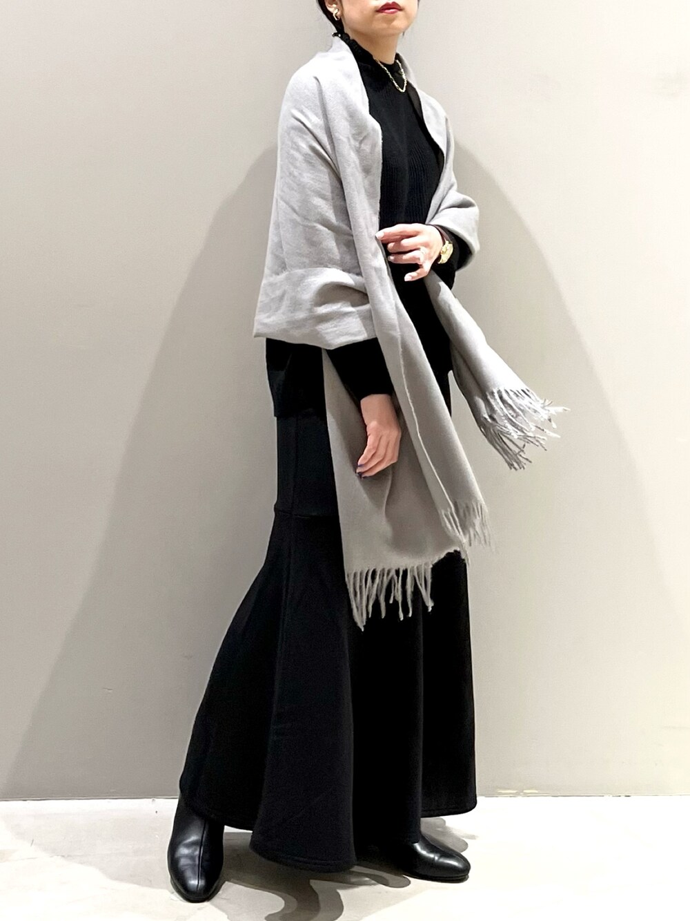 ブラック系のスカート、ブラック系のブーツ、ブラック系のニット/セーターを着用したレディースの秋コーディネートの2枚目の写真