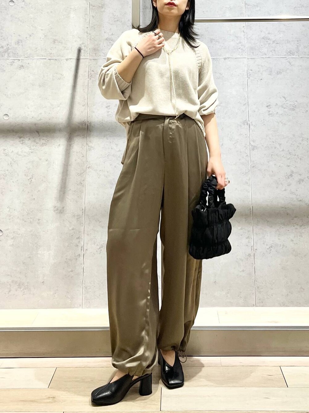 ブラック系のショルダーバッグ、ブラック系のパンプス、イエロー系のその他パンツを着用したレディースの冬コーディネートの3枚目の写真