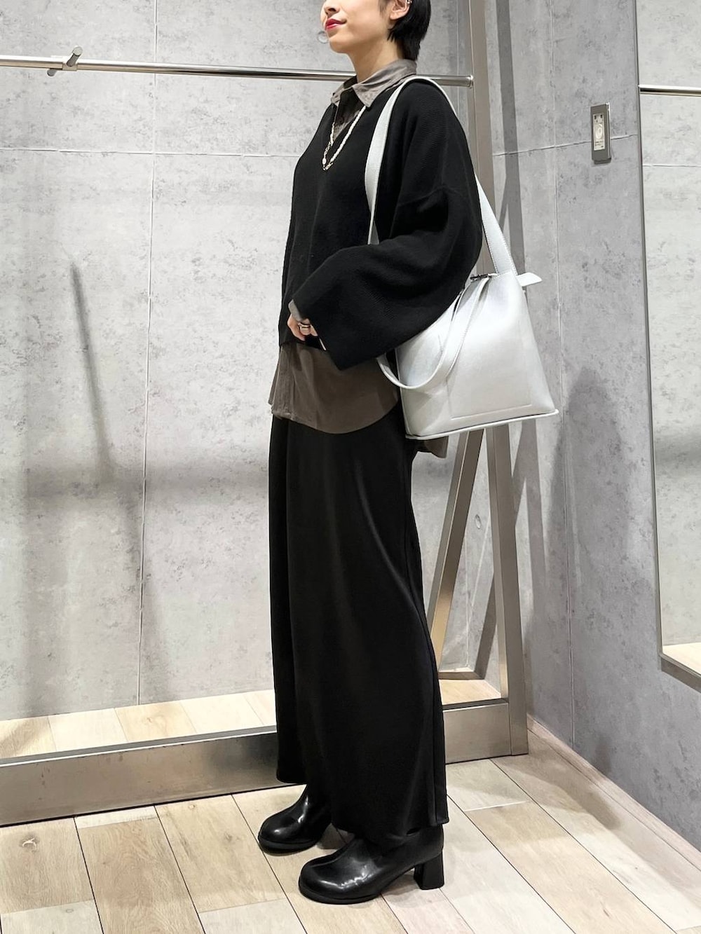 ブラック系のスカート、ブラック系のニット/セーター、グレー系のシャツ/ブラウスを着用したレディースの秋コーディネートの3枚目の写真