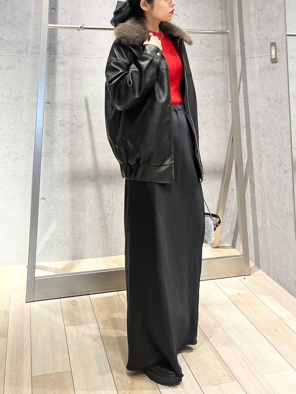 ブラック系のブーツ、オレンジ系のニット/セーター、ブラック系のスカートを着用したレディースの冬コーディネートの6枚目の写真