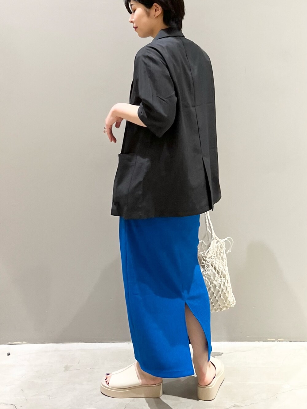 ブルー系のスカート、ホワイト系のトートバッグ、ベージュ系のサンダルを着用したレディースの夏コーディネートの4枚目の写真