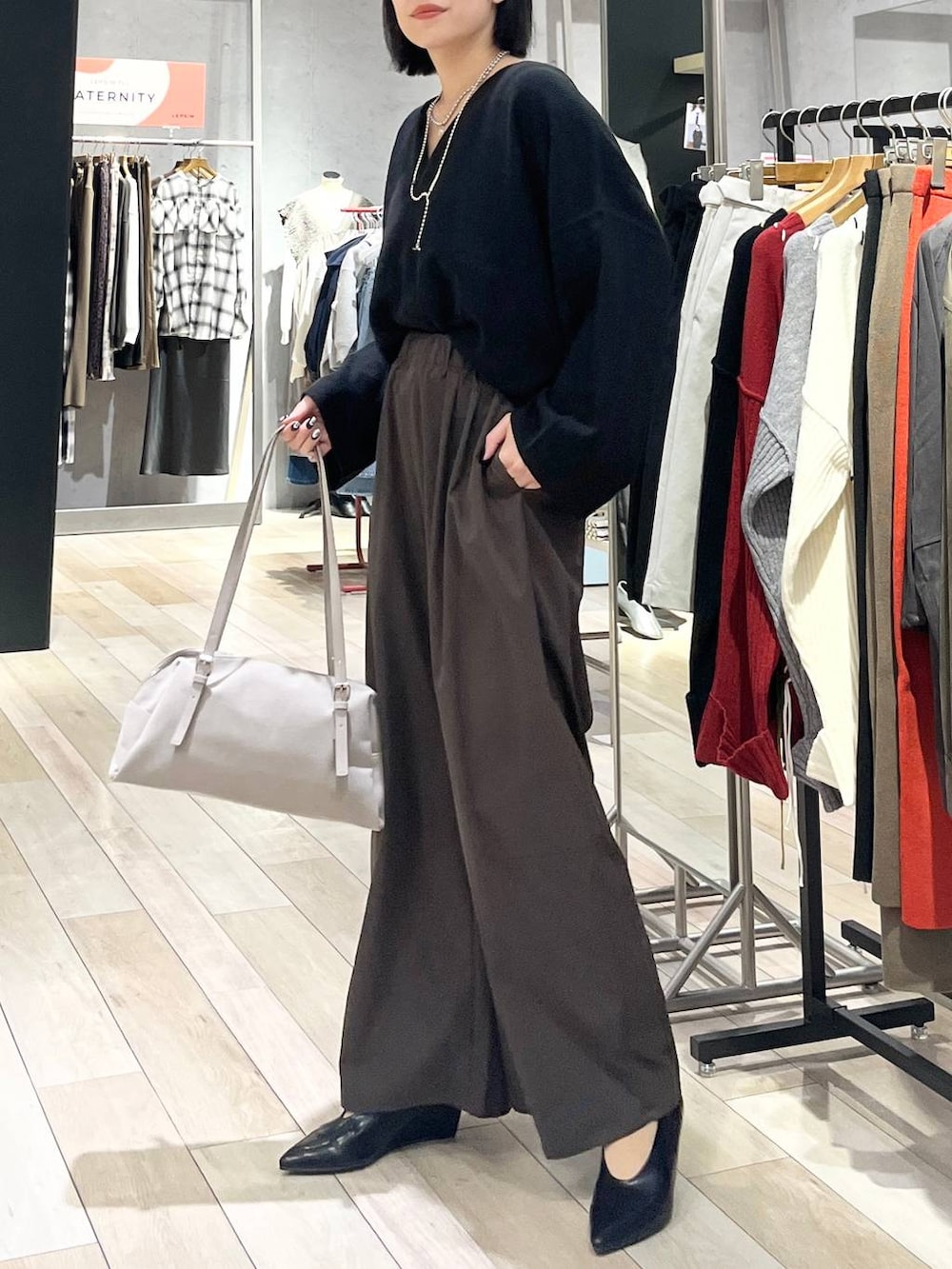 ブラック系のニット/セーター、ブラウン系のその他パンツ、ベージュ系のボストンバッグを着用したレディースの秋コーディネートの3枚目の写真