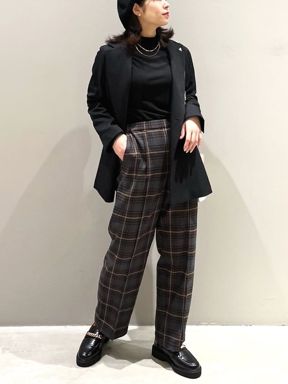 ブラウン系のスラックス、ブラック系のローファー、ホワイト系のショルダーバッグを着用したレディースの秋コーディネートの2枚目の写真