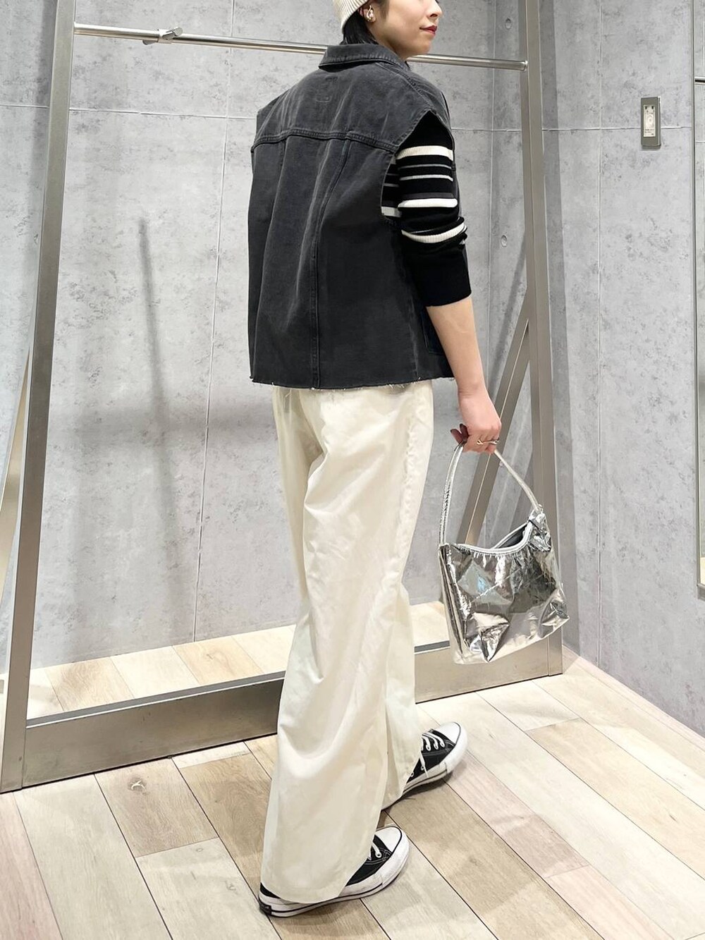 シルバー系のハンドバッグ、グレー系のベスト、ホワイト系のその他パンツを着用したレディースの冬コーディネートの3枚目の写真