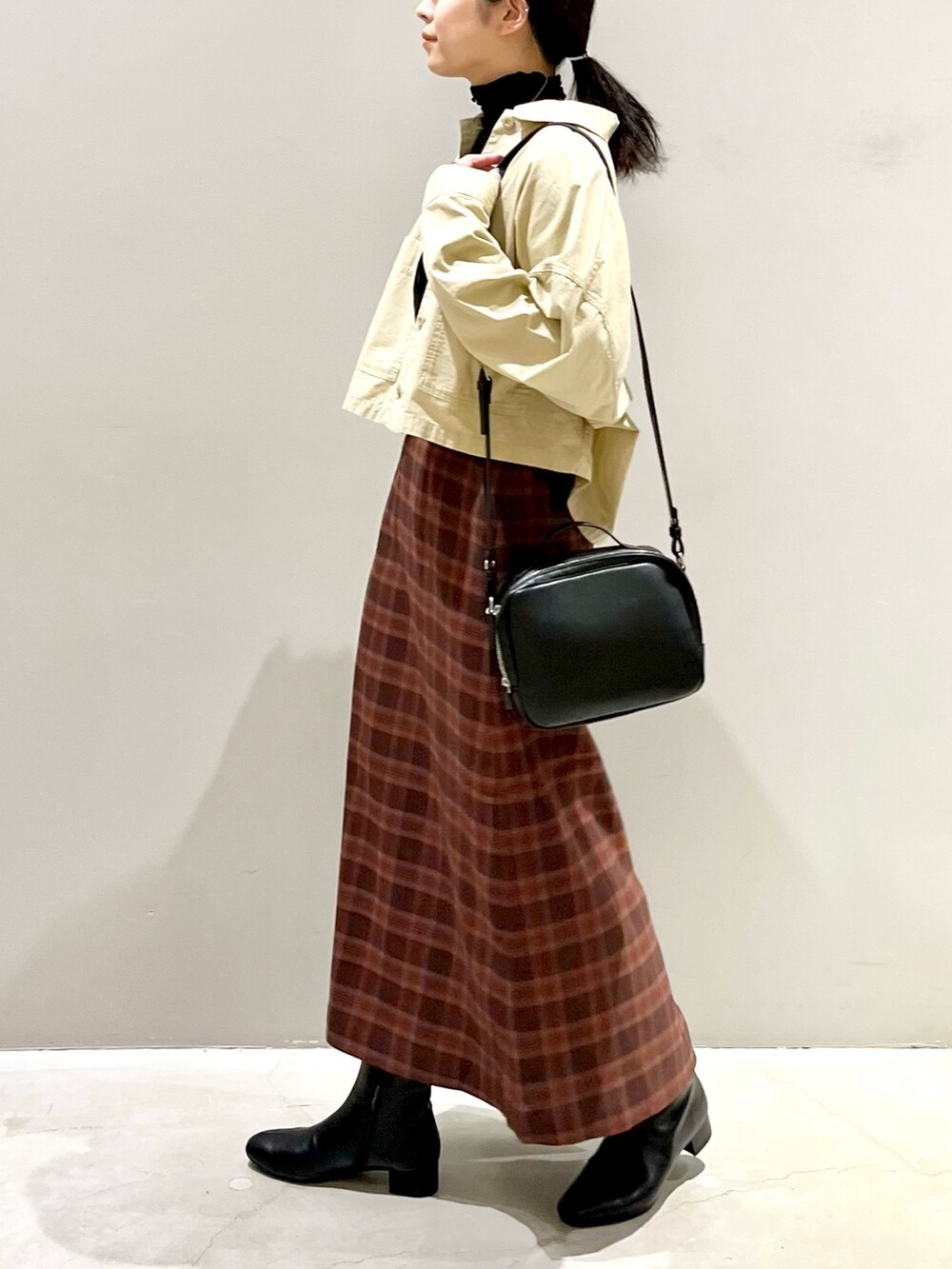 ブラック系のブーツ、レッド系のスカート、ブラック系のバッグを着用したレディースの秋コーディネートの2枚目の写真