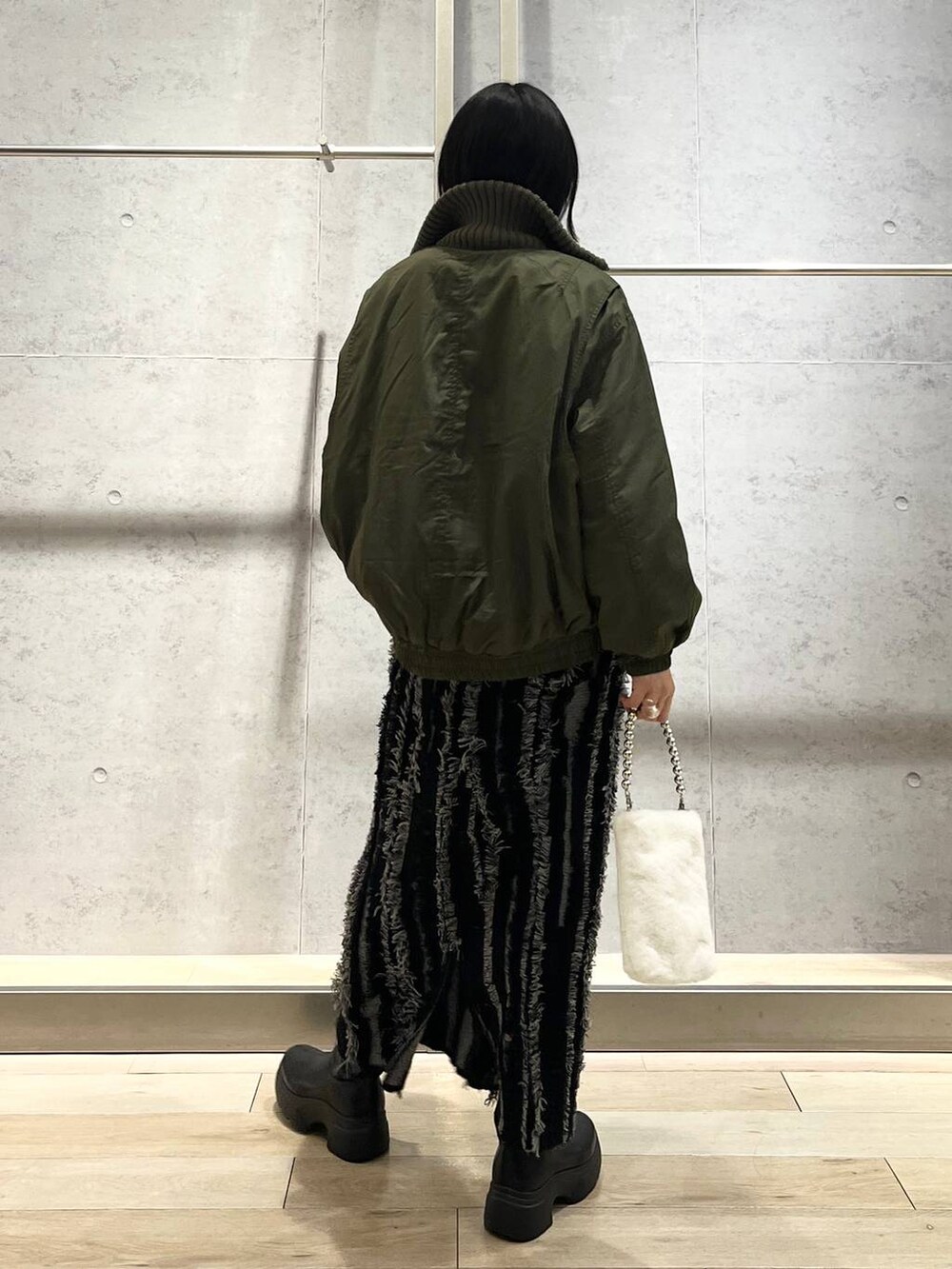 ブラック系のスカート、ブラック系のTシャツ/カットソー、ブラック系のブーツを着用したレディースの秋コーディネートの3枚目の写真