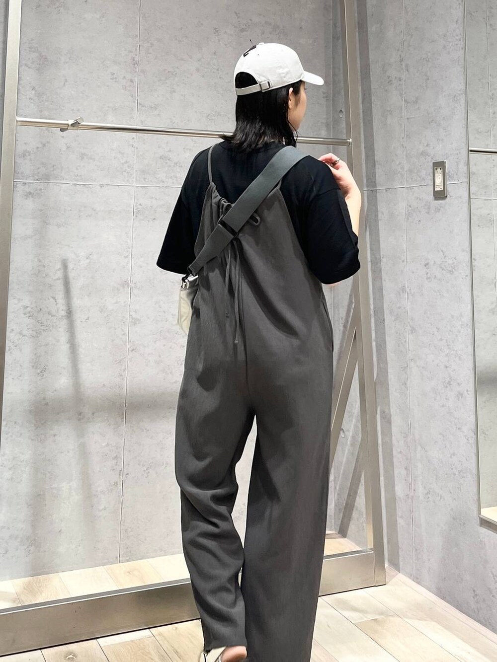 グレー系のサロペット/オーバーオール、グレー系のクラッチバッグ、ホワイト系のサンダルを着用したレディースの夏コーディネートの3枚目の写真