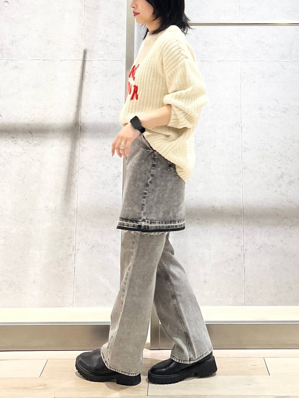 シルバー系のショルダーバッグ、ブラック系のデニムパンツ、ブラック系のブーツを着用したレディースの秋コーディネートの3枚目の写真