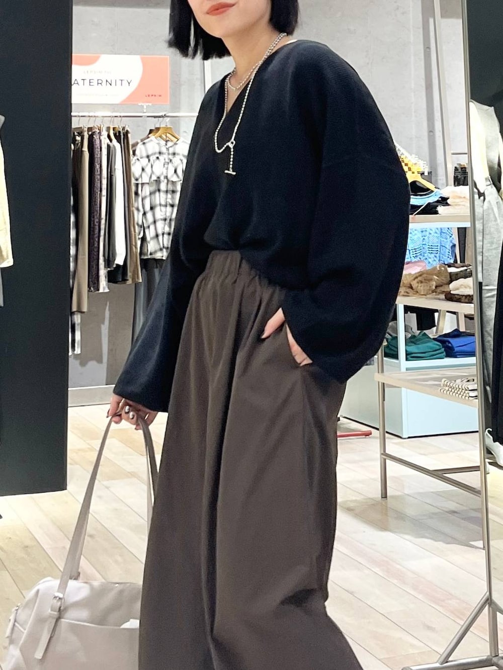 ブラック系のニット/セーター、ブラウン系のその他パンツ、ベージュ系のボストンバッグを着用したレディースの秋コーディネートの6枚目の写真