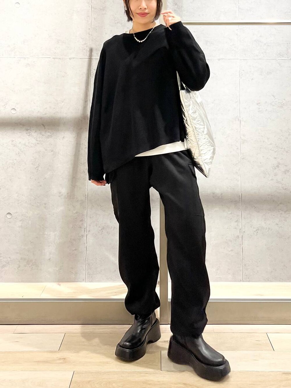 ブラック系のニット/セーター、ホワイト系のTシャツ/カットソー、ブラック系のブーツを着用したレディースの秋コーディネートの9枚目の写真