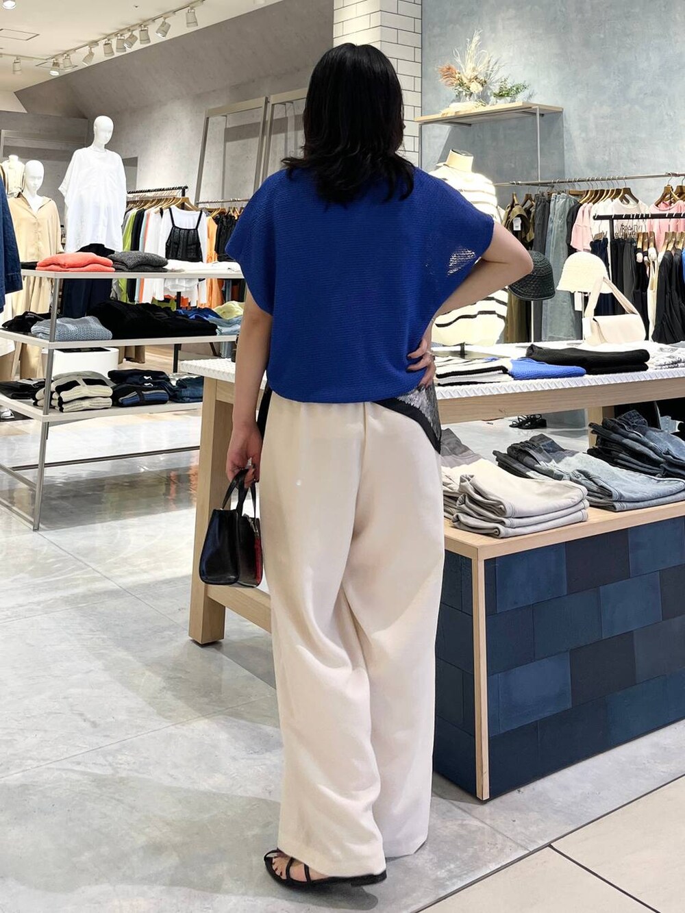 ブルー系のニット/セーター、ホワイト系のその他パンツ、ブラック系のサンダルを着用したレディースの春コーディネートの4枚目の写真